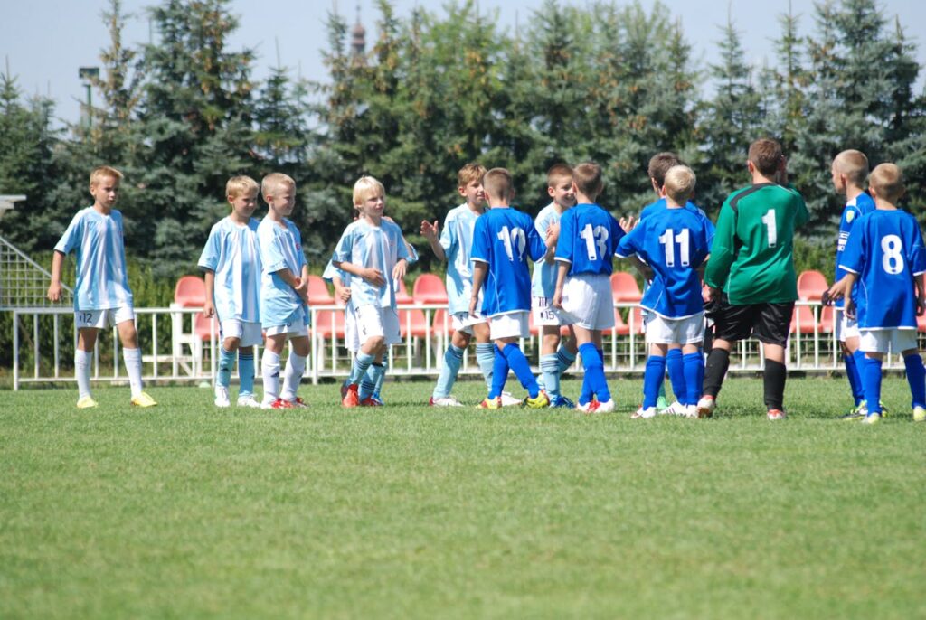 A group of young soccer players shakes hands on a sunny day, showing great sportsmanship.